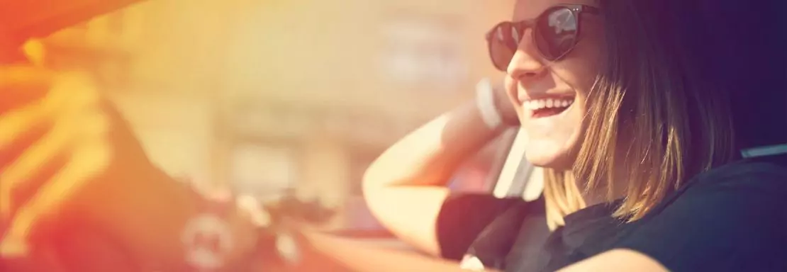 Femme souriante conduisant une voiture par temps ensoleillé