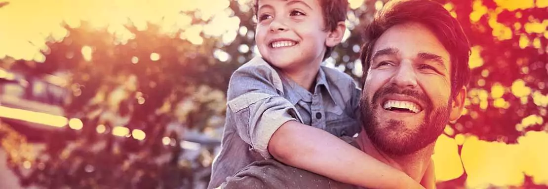 Un père et son fils souriant en extérieur