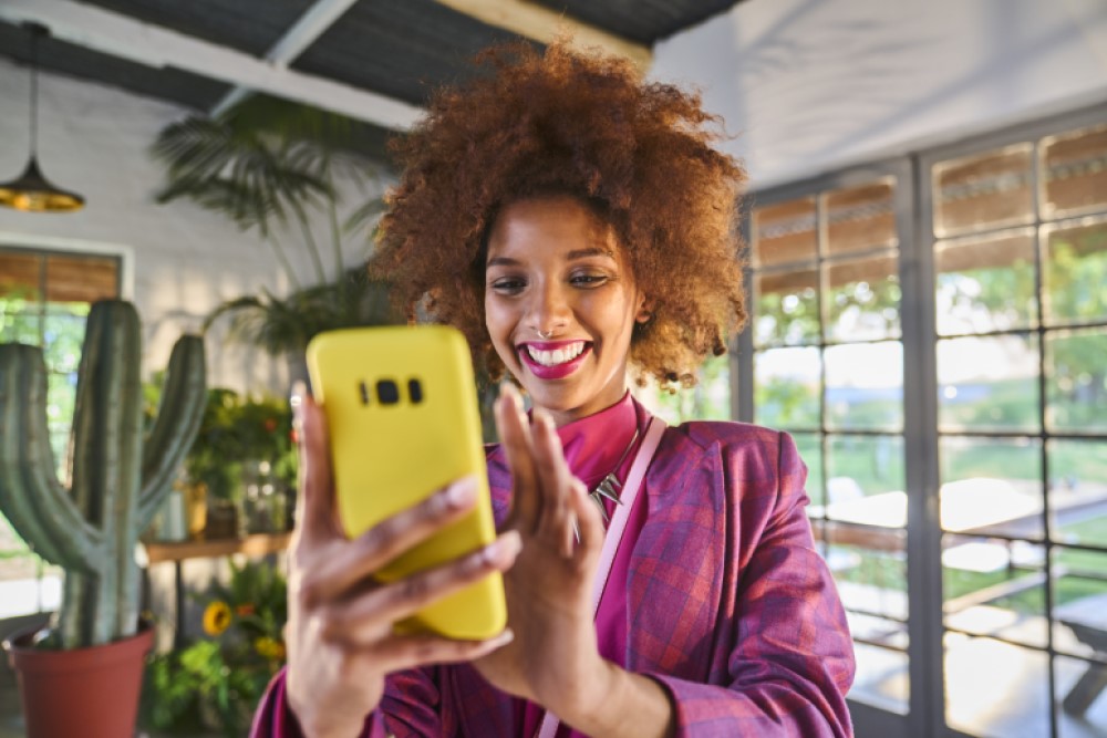 Jeune femme souriante qui navigue sur l’appli mobile Cofidis