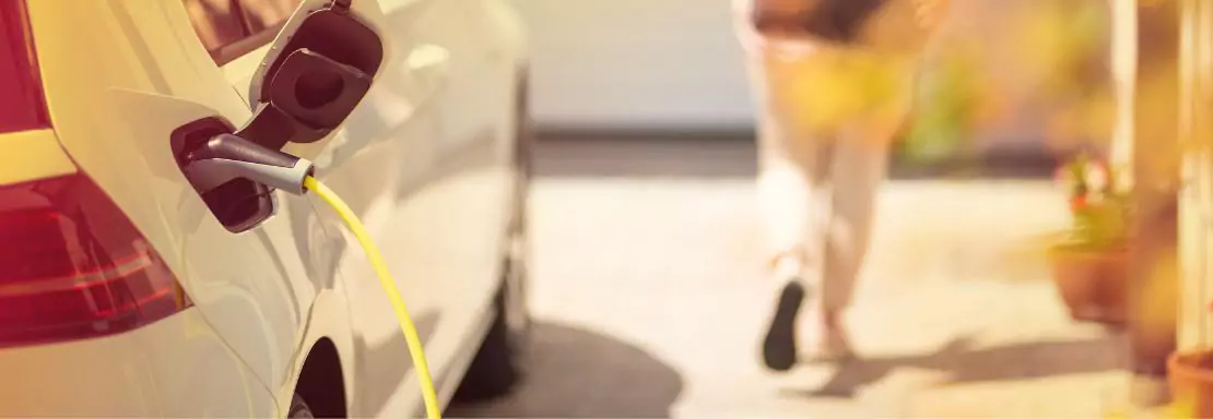 Voiture électrique en charge, avec une personne en arrière-plan