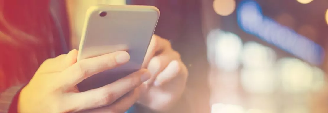 Personne tenant un smartphone sous lumière urbaine tamisée