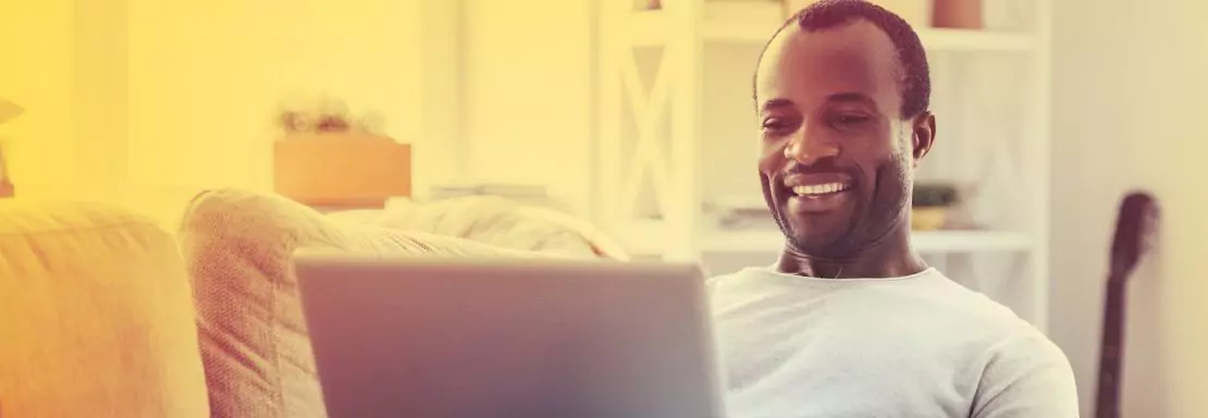 Un homme souriant utilise un ordinateur portable à la maison