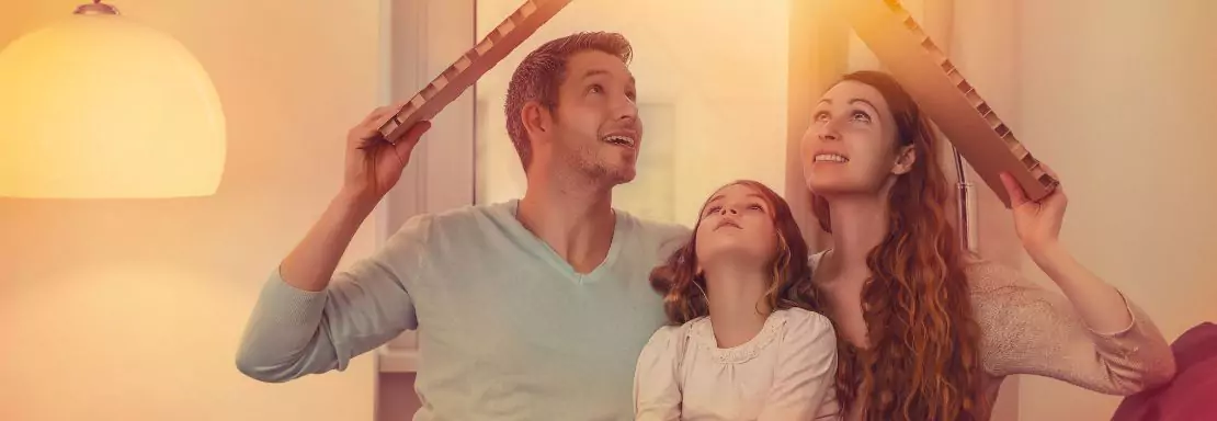 Famille sourtiante formant un toit en carton au-dessus de leur tête.