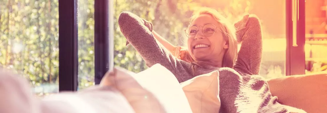 Femme joyeuse se relaxant près d'une fenêtre ensoleillée
