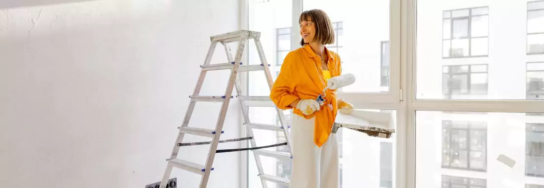 Femme peignant un mur blanc près d'une fenêtre