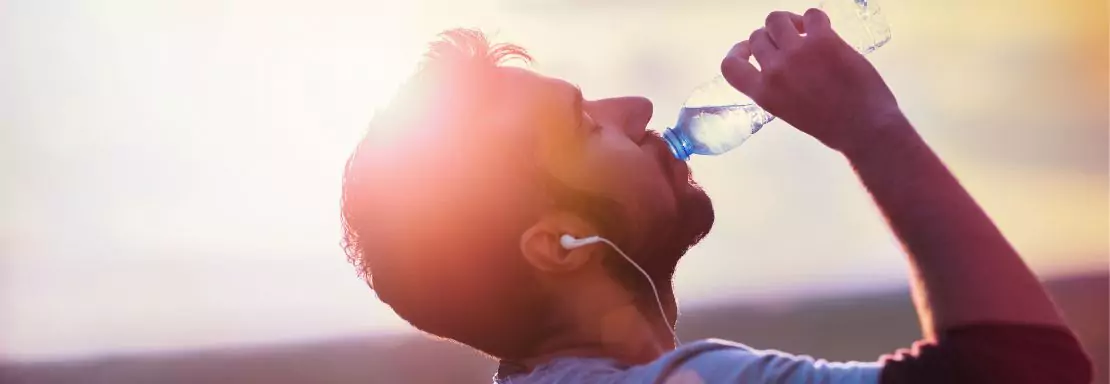 Un homme boit de l'eau en plein soleil