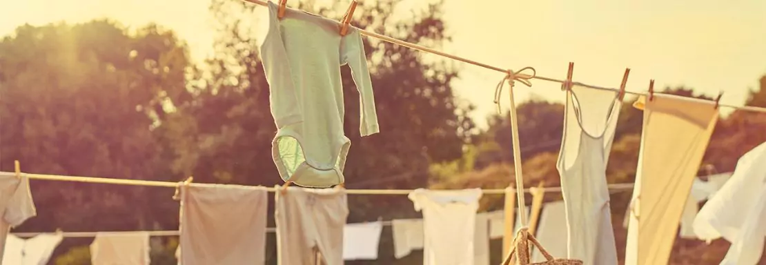 Vêtements et body de bébé séchant au soleil couchant