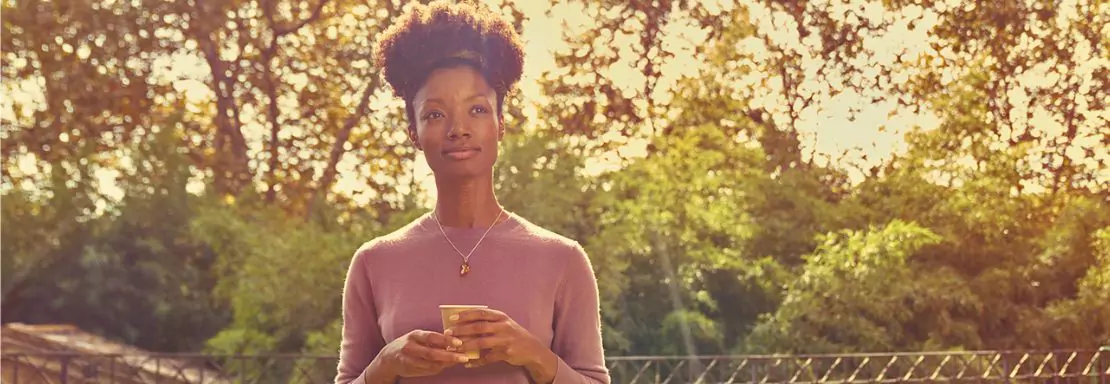 Femme tenant une carte bancaire parmi les arbres
