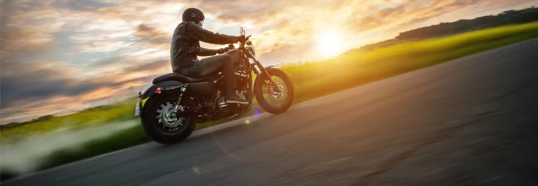 Moto roulant sur une route au coucher du soleil