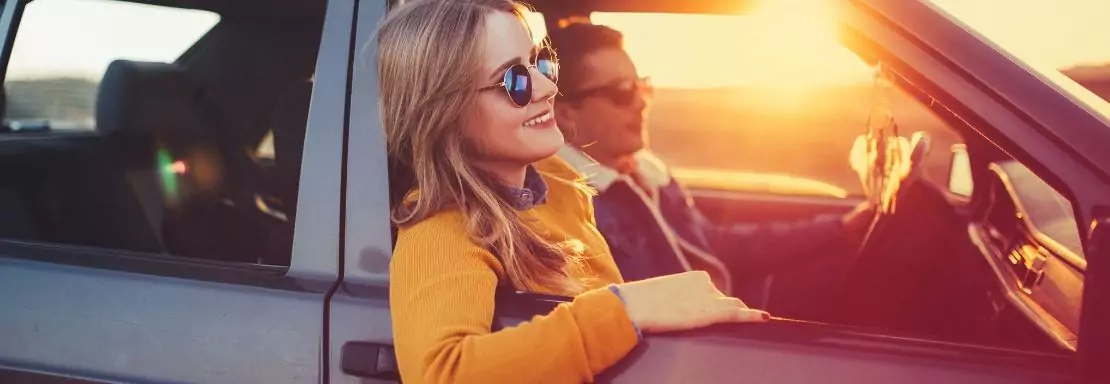 Une femme profite du coucher de soleil lors d’un trajet en voiture avec son ami