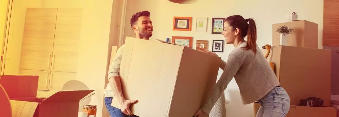 Un couple déplace un carton dans leur salon