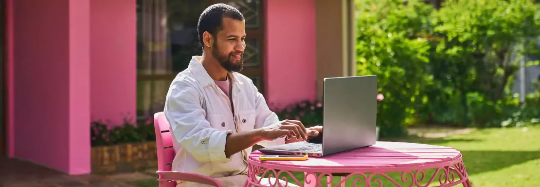 Homme travaillant sur un ordinateur portable dans un jardin coloré