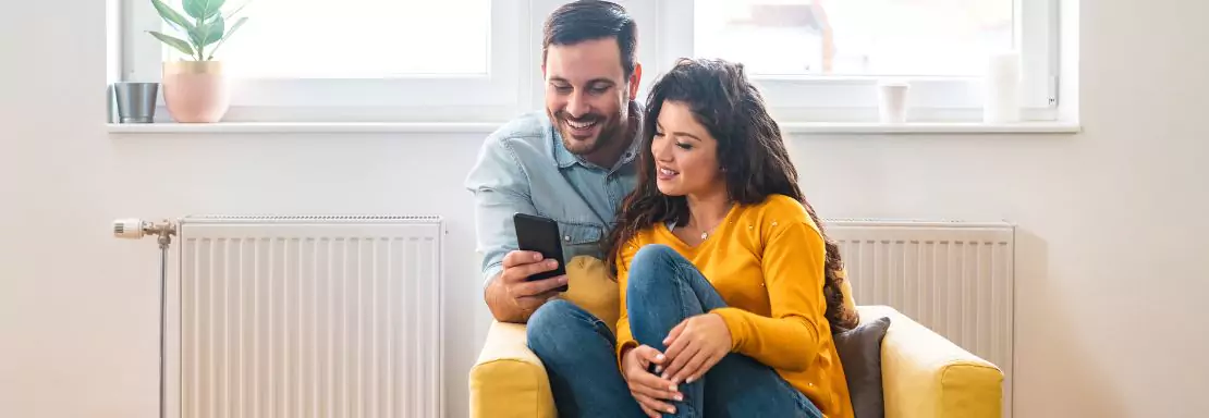 Couple heureux regardant un téléphone dans leur salon