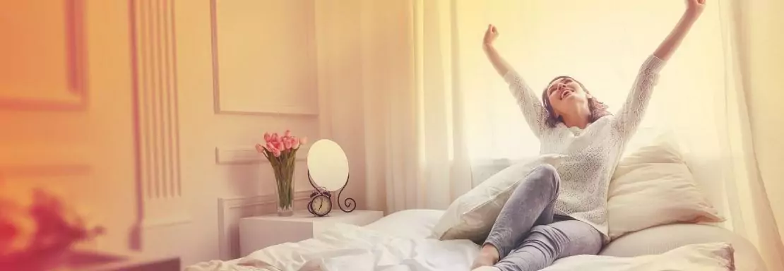 Femme s'étirant joyeusement le matin dans sa chambre