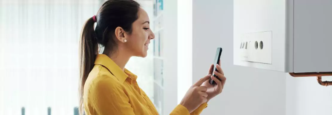 Femme utilisant un smartphone pour vérifier une chaudière