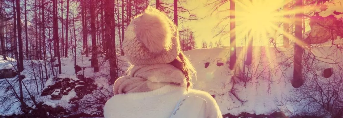 Personne admirant un lever de soleil dans la forêt enneigée