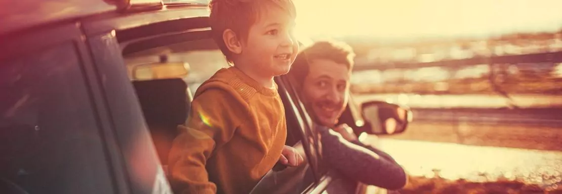 Un enfant et un adulte regardent dehors au coucher du soleil