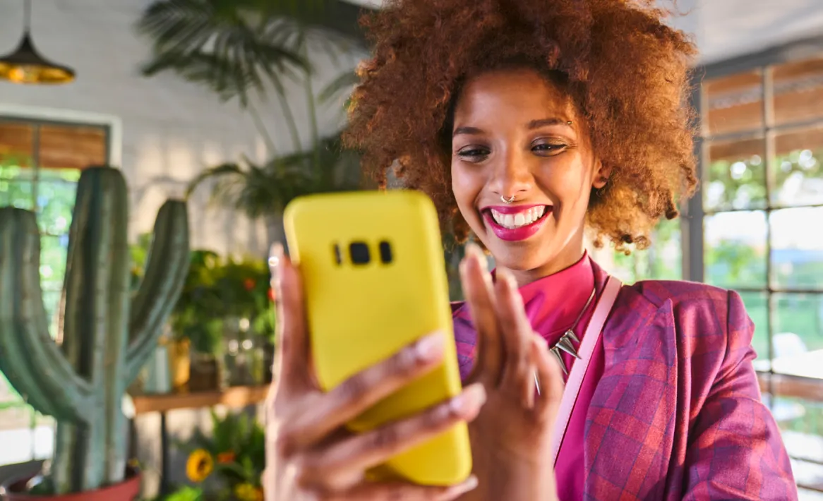 Une femme sourit en utilisant son téléphone