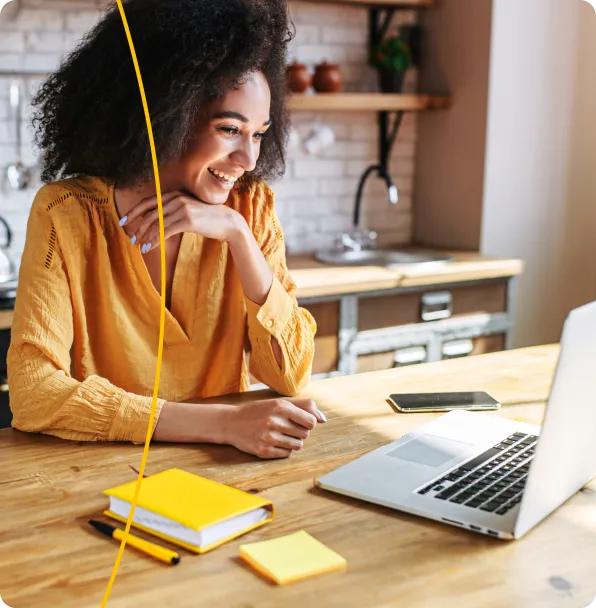 Une jeune femme souriante assise devant son ordinateur portable