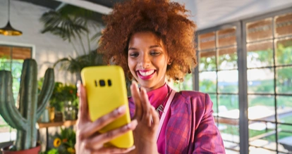 Une femme sourit en utilisant son téléphone