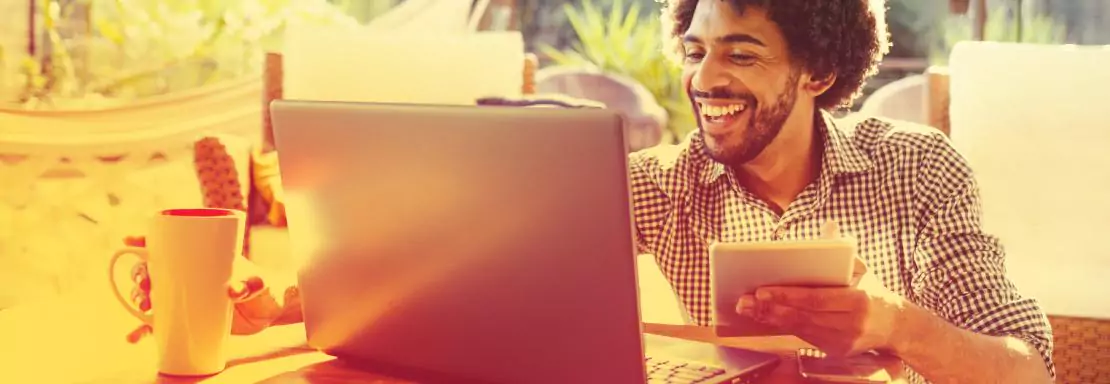 Man werkt thuis met laptop en tablet, koffie aanw