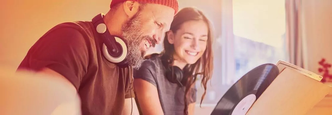 Vader en dochter genieten van muziek met hoofdtelefoons en vinylplaat