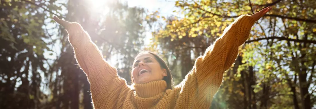 Vrouw in trui geniet buiten van de herfstzon