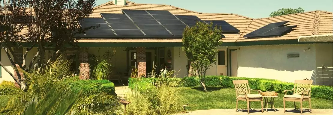 Huis met zonnepanelen bij zonnig weer en groene omgeving