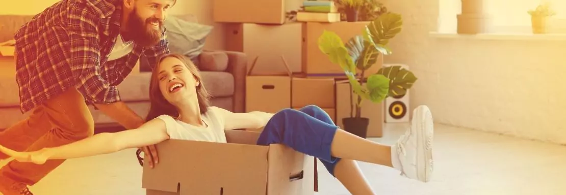 Man duwt vrouw in doos tijdens verhuizing, lachend plezier