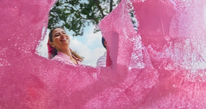 Een vrouw lacht terwijl ze roze verf aanbrengt met een verfroller