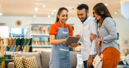 Trois personnes regardent une tablette en souriant dans un magasin