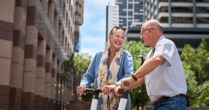 Twee mensen glimlachen terwijl ze op elektrische scooters rijden